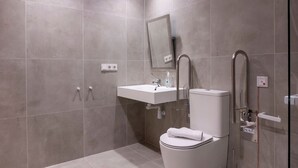 A modern bathroom with grey tiles, a white sink, a toilet, and a shower area. - VLC HOST - Palau A (Valencia)