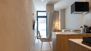 Una cocina moderna con estufa integrada, un comedor con sillas de mimbre y vistas a través de un ventanal.