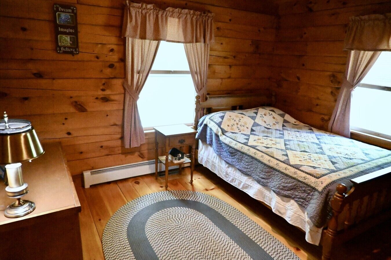 Ein Schlafzimmer einer Holzhütte mit Bett, Nachttisch, Lampe und Heizkörper.
