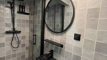 Une salle de bain moderne équipée d’une douche, de toilettes, d’un lavabo et d’un miroir rond.