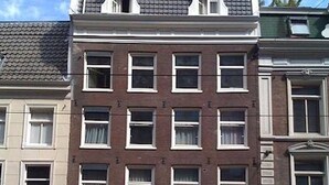 A multi-story building with a central entrance featuring a wooden door and a small balcony. - Room/private bathroom in centre (Amsterdam)