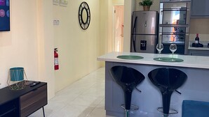 A modern kitchen with a central island, bar stools, a refrigerator, and a wall-mounted clock. - Condo in Gros Islet 10 mins drive to beach (Gros Islet)