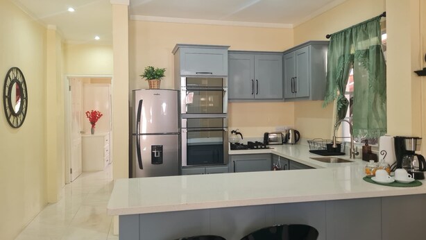 A modern kitchen with grey cabinets, a stainless steel refrigerator, a built-in oven, and a gas stove. - Condo in Gros Islet 10 mins drive to beach (Gros Islet)