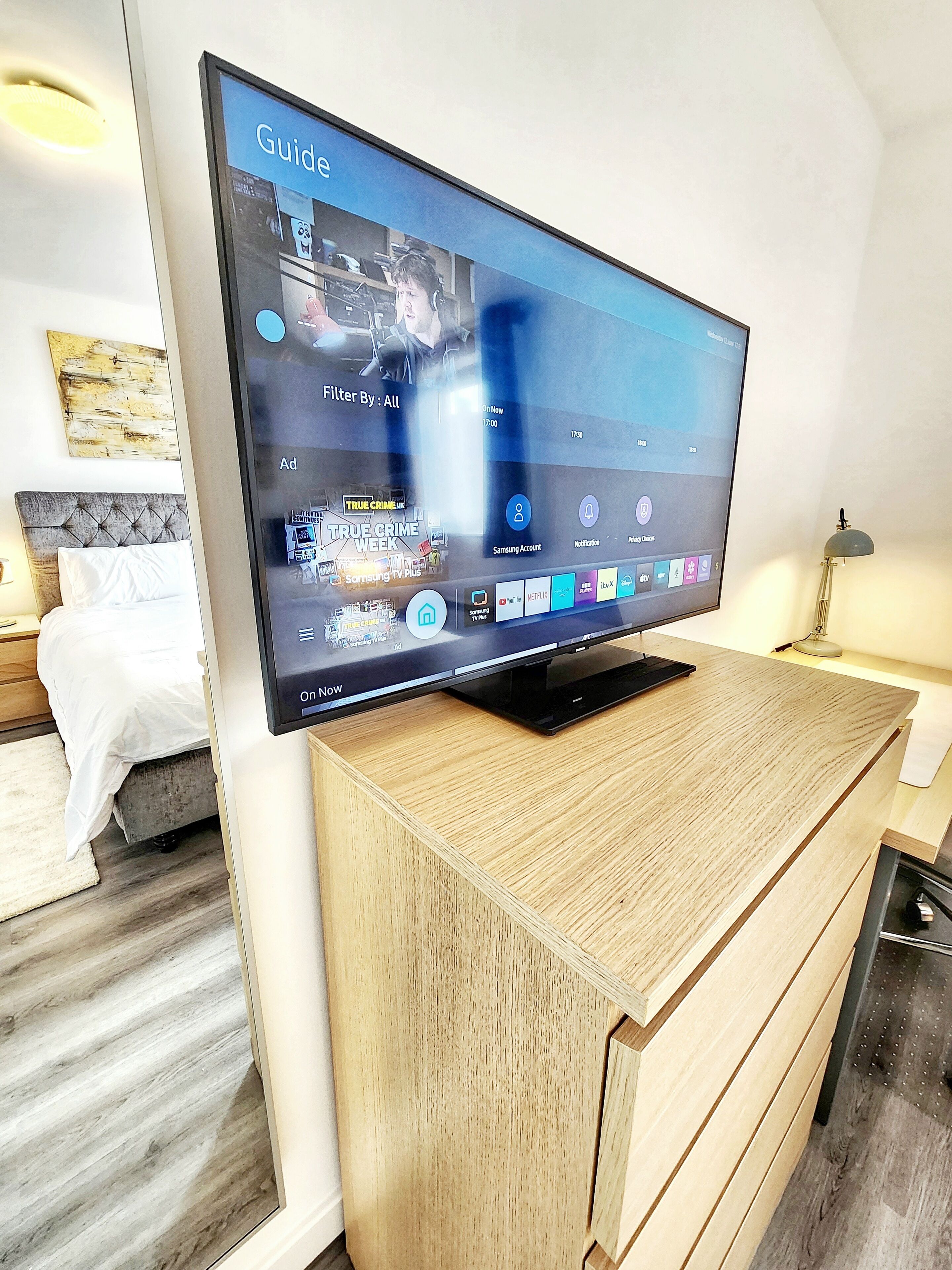 Un téléviseur à écran plat posé sur un meuble en bois dans une chambre d’hôtel.