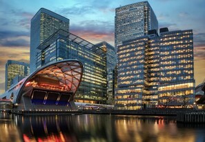 A modern cityscape with high-rise buildings and a distinctive curved structure near a waterfront.