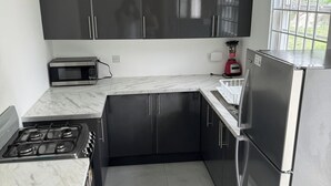 A compact kitchen with dark cabinets, a microwave, a gas stove, and a refrigerator.