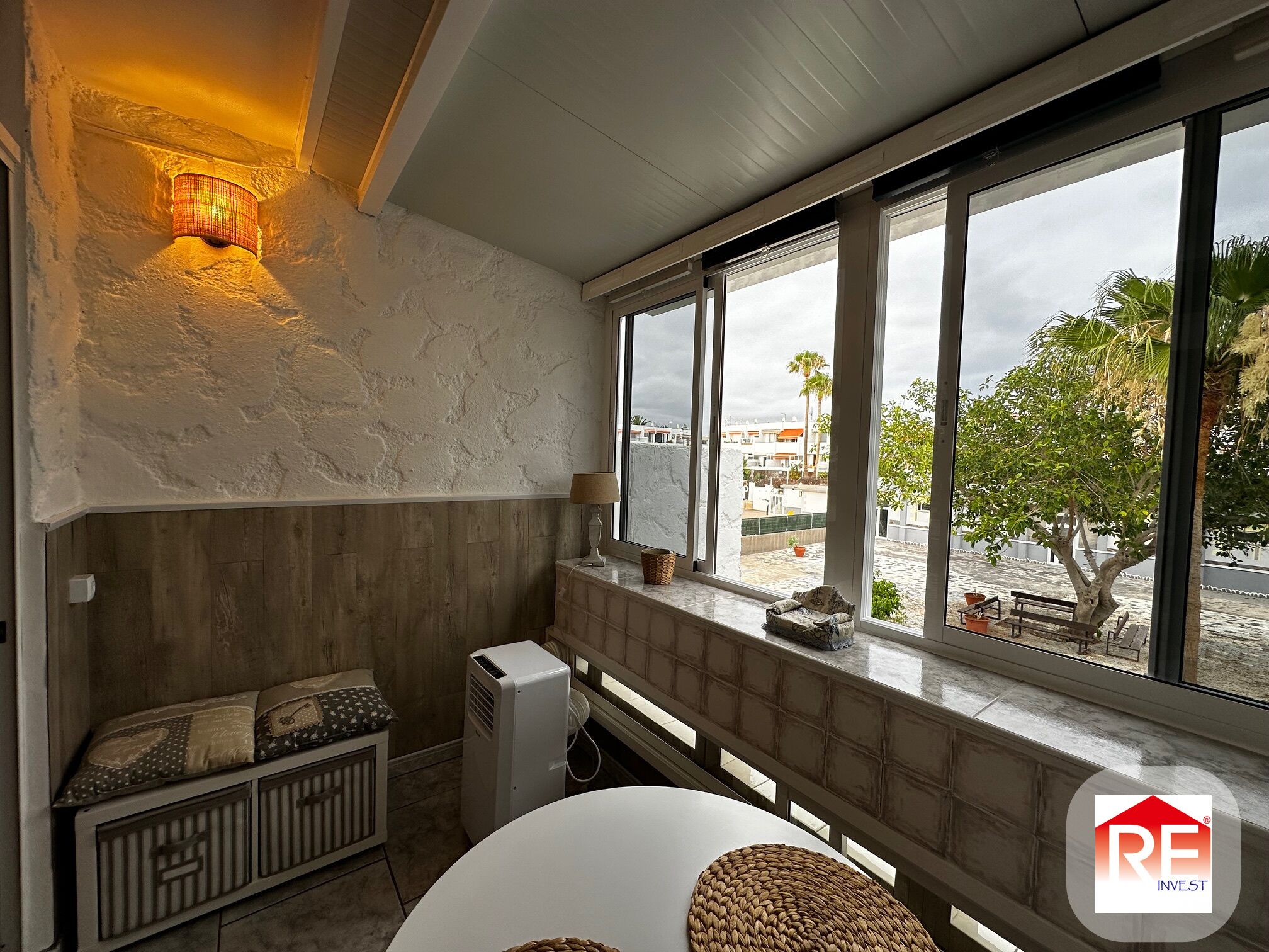 A room with a large window, a radiator, a table, and a lamp.