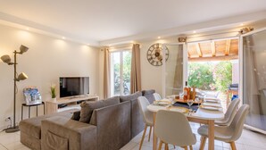 Een moderne woonkamer met een bank, televisie, eettafel en stoelen.