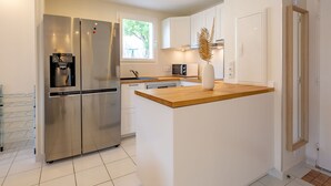 Een moderne keuken met een roestvrijstalen koelkast, een houten aanrechtblad en witte kasten.