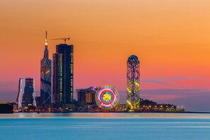 Une vue sur une ville au crépuscule, avec des bâtiments illuminés et une grande roue.