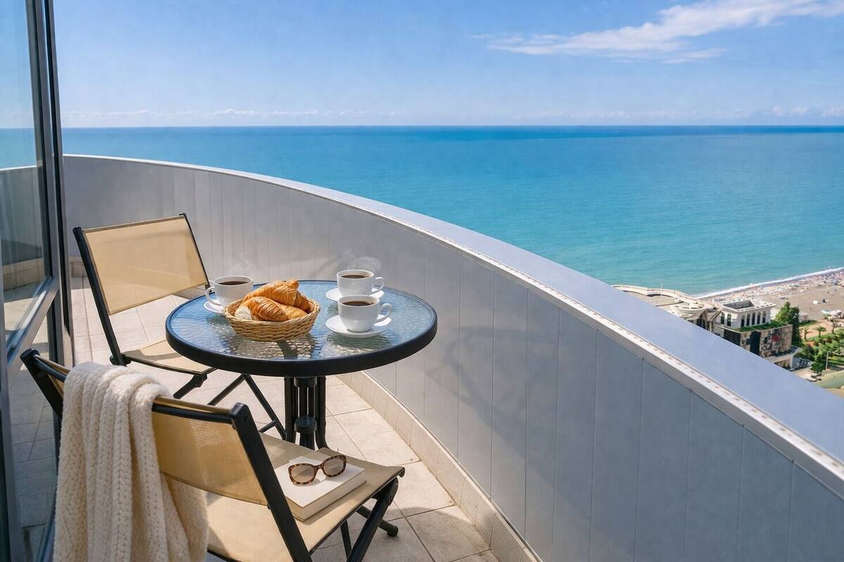 A balcony with a table, chairs, and a view of the sea.