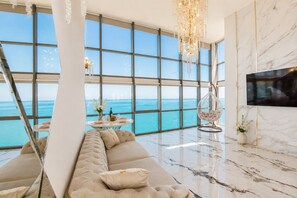 A modern living room with a large window overlooking the sea, a hanging chair, a sofa, and a flat-screen TV mounted on the wall. - Panorama (Batumi)