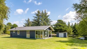A single-story building with a covered patio, surrounded by a well-maintained lawn and trees.
