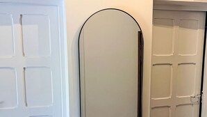 Un pasillo con tres puertas blancas, una con diseño de rejilla, otra de panel único y una tercera con parte superior curva.