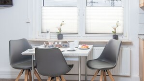A dining area with a table, chairs, and a window with blinds. - Apartment Stark by Interhome (Norddeich)