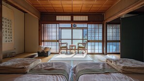 Una tradizionale stanza giapponese con pavimento in tatami, soffitto in legno basso, porte scorrevoli shoji e vista attraverso le porte.