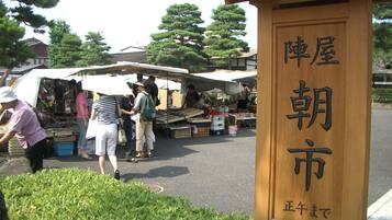 A wooden sign with Japanese characters, indicating a market area with people shopping and vendors under umbrellas.