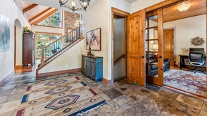 A spacious foyer with a wooden staircase, a chandelier, and a patterned rug. - Luxurious 5BDR Getaway w/ Hot Tub & Mountain Views (Blue River)