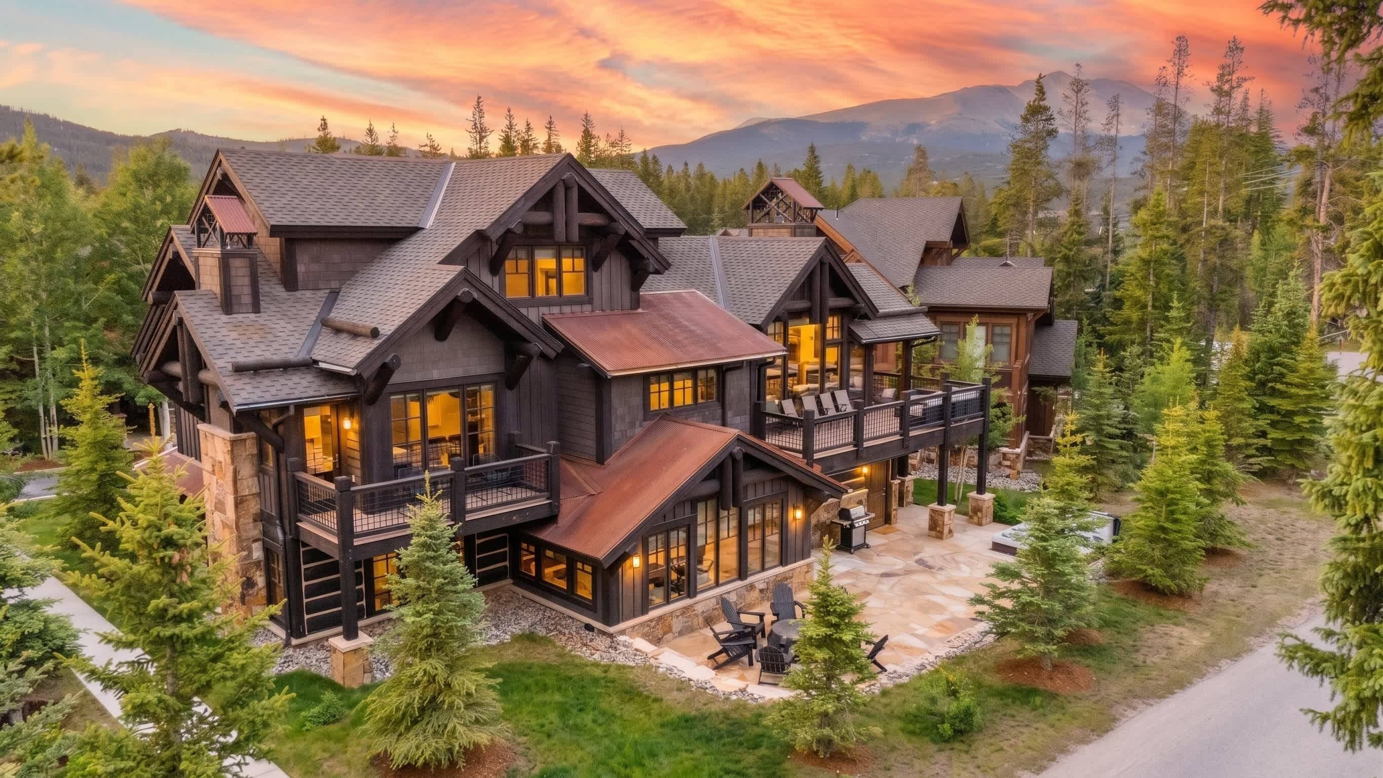 A large, multi-story lodge with a prominent balcony and a stone patio area.