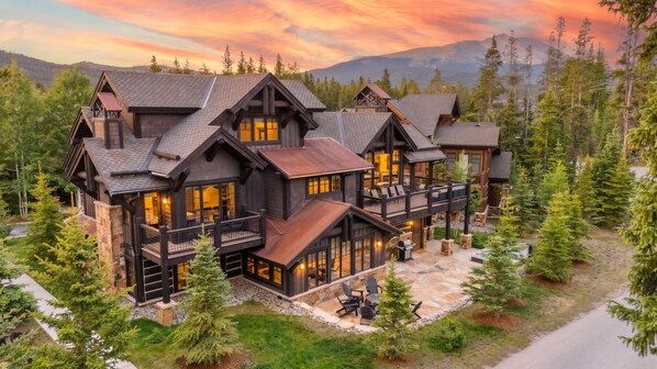 A large, multi-story lodge with a prominent balcony and a stone patio area.