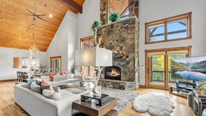 A spacious living room with a stone fireplace, wooden ceiling, and large windows. - Stunning 6BR Lodge w/ Beautiful Mt. Quandary Views (Blue river)