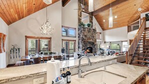 A spacious kitchen with granite countertops, a stone fireplace, and a large window overlooking a deck. - Stunning 6BR Lodge w/ Beautiful Mt. Quandary Views (Blue river)