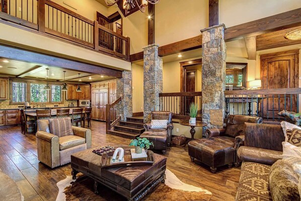 A spacious living area with leather sofas, a coffee table, and a stone pillar. - Breck Executive Lodge | Theater + Private Sauna (Breckenridge)