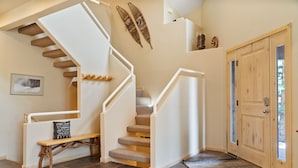 Eine Treppe mit weißen Geländern, einer Bank und einer Tür mit Glasscheiben.