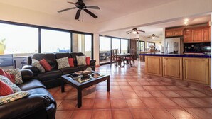A spacious living room with a black leather sofa, a coffee table, and a ceiling fan. - A-609 Vacation in this Exquisite Spacious 2-bedroom condominium! (Cabo San Lucas)