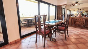 A dining area with a table and chairs, a ceiling fan, and a view through a glass door to an outdoor patio. - A-609 Vacation in this Exquisite Spacious 2-bedroom condominium! (Cabo San Lucas)