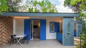 A modern outdoor kitchen area with a dining table and chairs, a blue door, and a satellite dish. - Cosy apartment in villa for 4 guests with WIFI, A/C, TV, terrace and pets allowed (San Michele Al Tagliamento)
