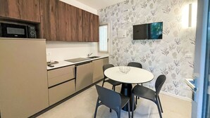 A compact kitchen with a microwave, sink, and a dining area with a round table and four chairs. - Cosy apartment in villa for 4 guests with WIFI, A/C, TV, terrace and pets allowed (San Michele Al Tagliamento)