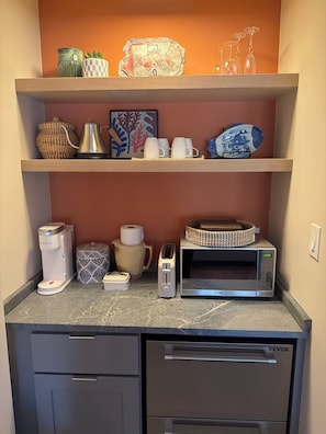 A kitchenette with a coffee maker, toaster, microwave, and a cabinet with drawers.