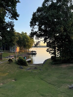 A lakeside property with a dock, grassy areas, and trees.