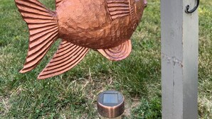 Une sculpture de poisson en cuivre est suspendue à une structure, et le numéro 113 est visible.