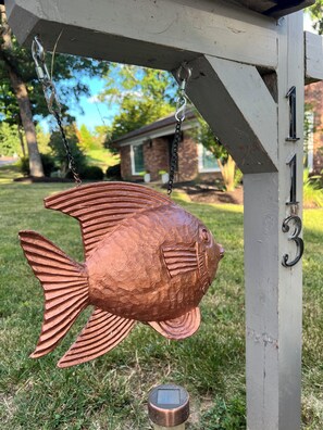 A copper fish sculpture hanging from a structure with the number 113 visible.