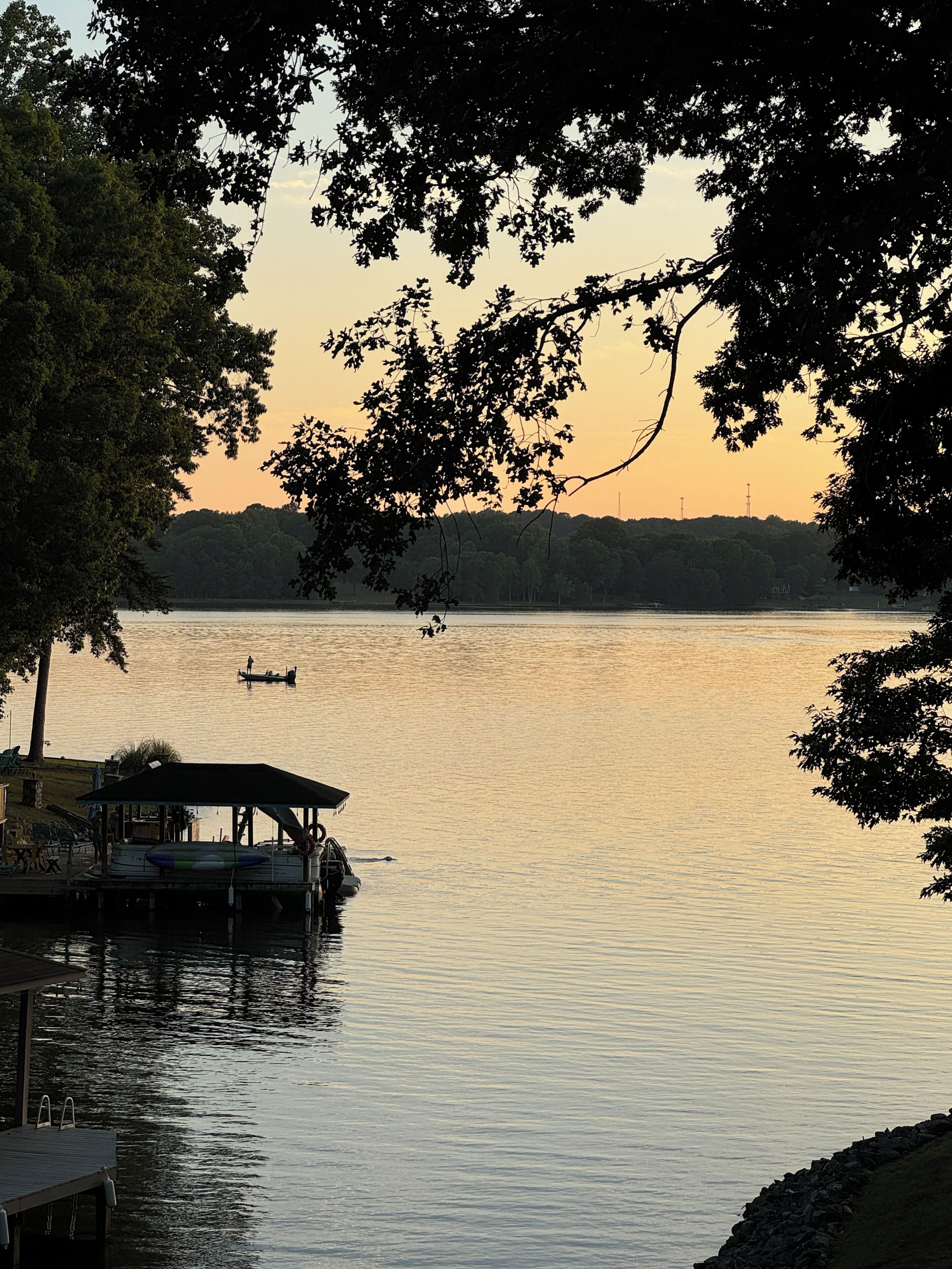 A lakeside view with a dock, a boat, and a distant shoreline.