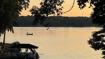 A lakeside view with a dock, a boat, and a distant shoreline.
