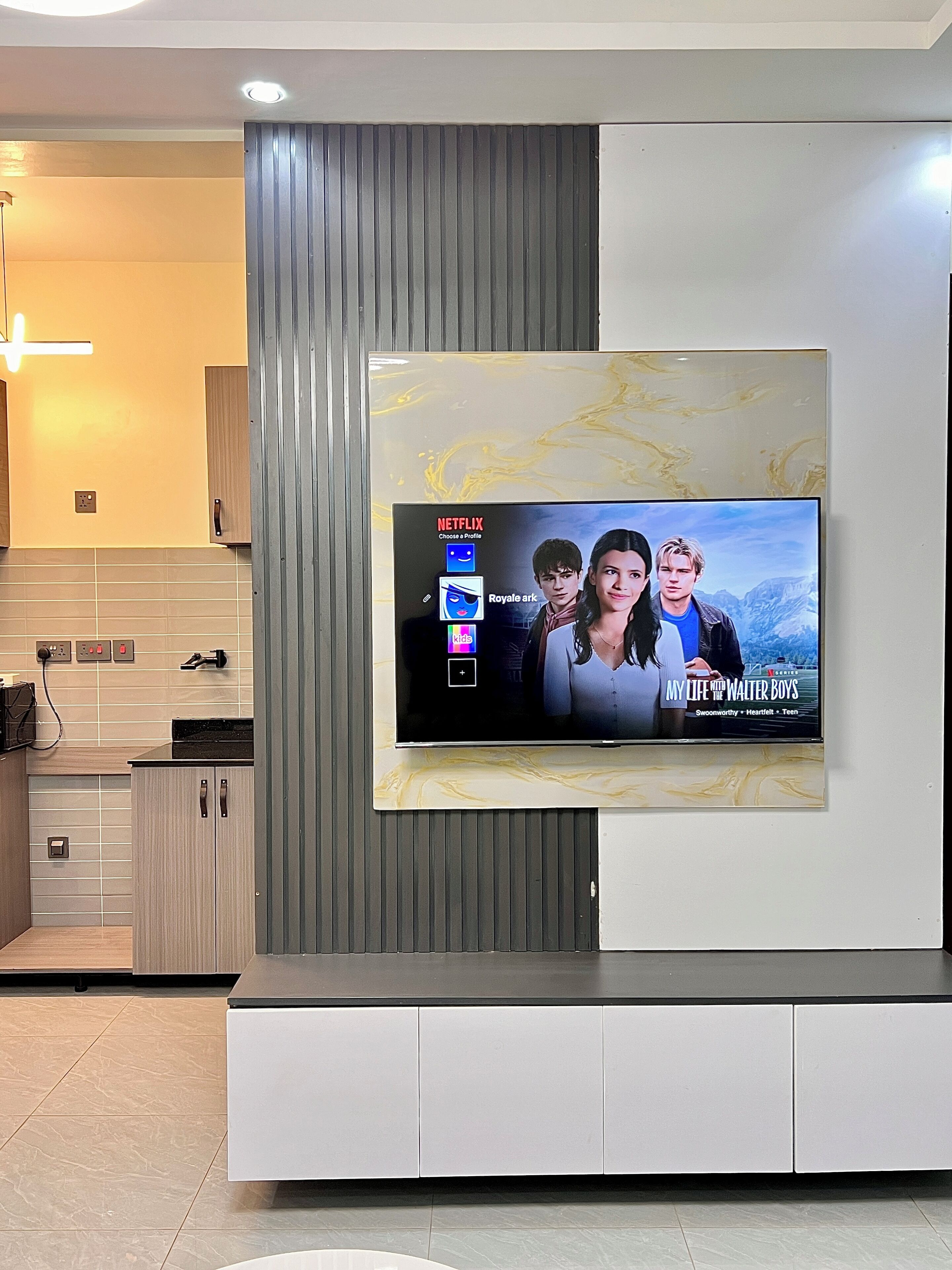 Un salon moderne avec un téléviseur fixé au mur diffusant la série « Ma vie avec les frères Walter ».