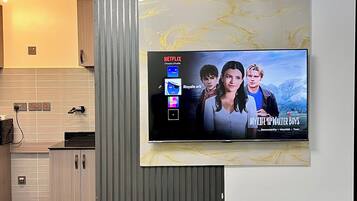 Un salon moderne avec un téléviseur fixé au mur diffusant la série « Ma vie avec les frères Walter ».