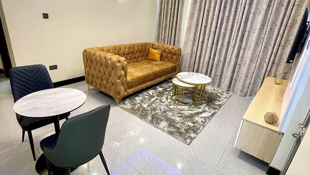 A modern living room with a sofa, a coffee table, and a dining area with chairs. - Lee Villas  (Kampala)