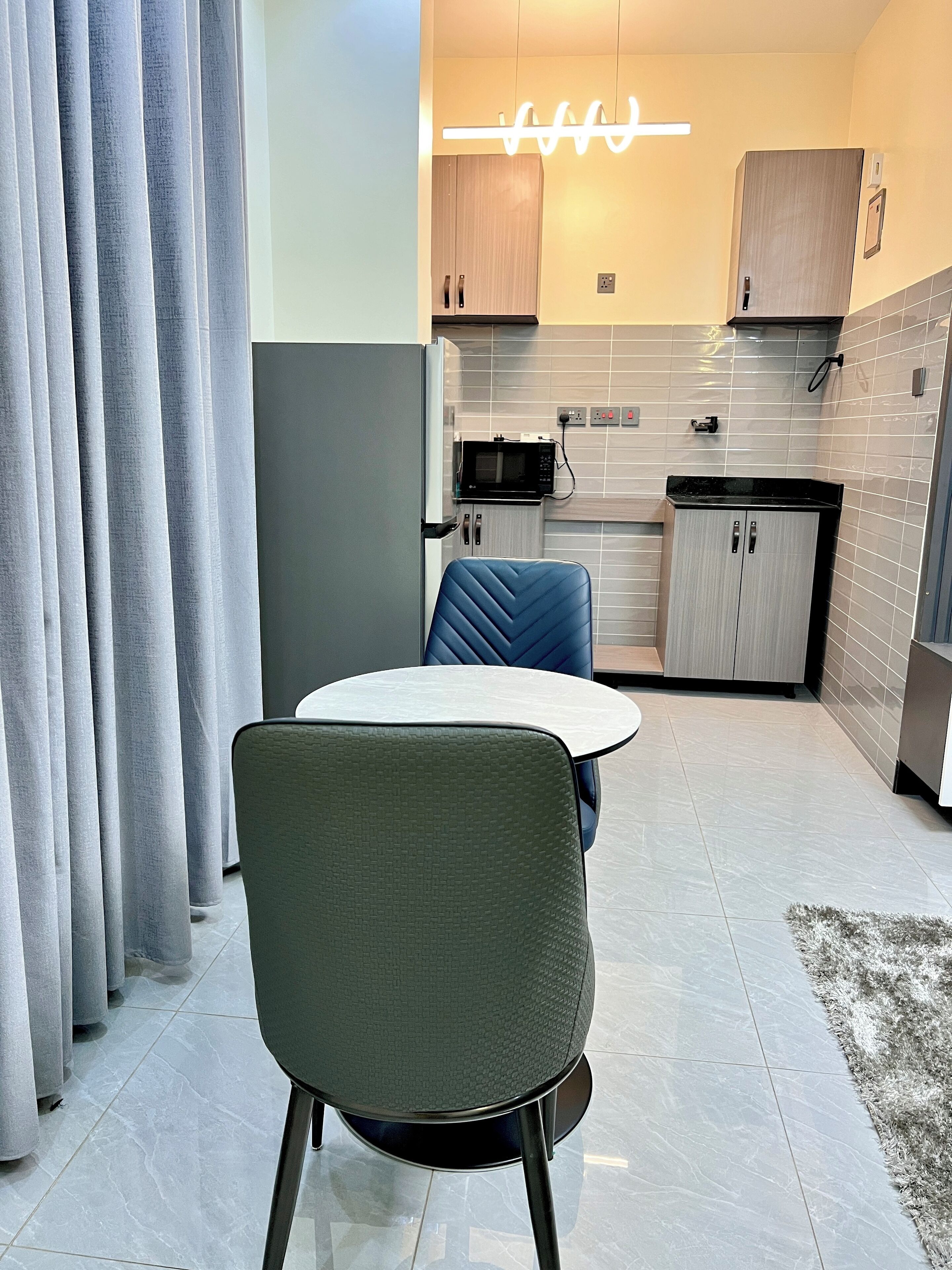 A modern kitchen with a dining area, featuring a microwave, cabinets, and a table with chairs.