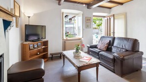 Ein Wohnzimmer mit Fernseher, Sofa und Tisch.