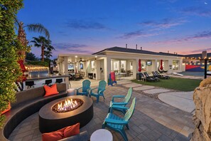 An outdoor patio area with a fire pit, seating, and a poolside bar. - Wonderscape - Lion Slide, Arcade, Pickleball, Spa (Indio)