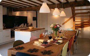 A modern kitchen with a wooden island, pendant lights, and a dining area with a wooden table set for a meal.