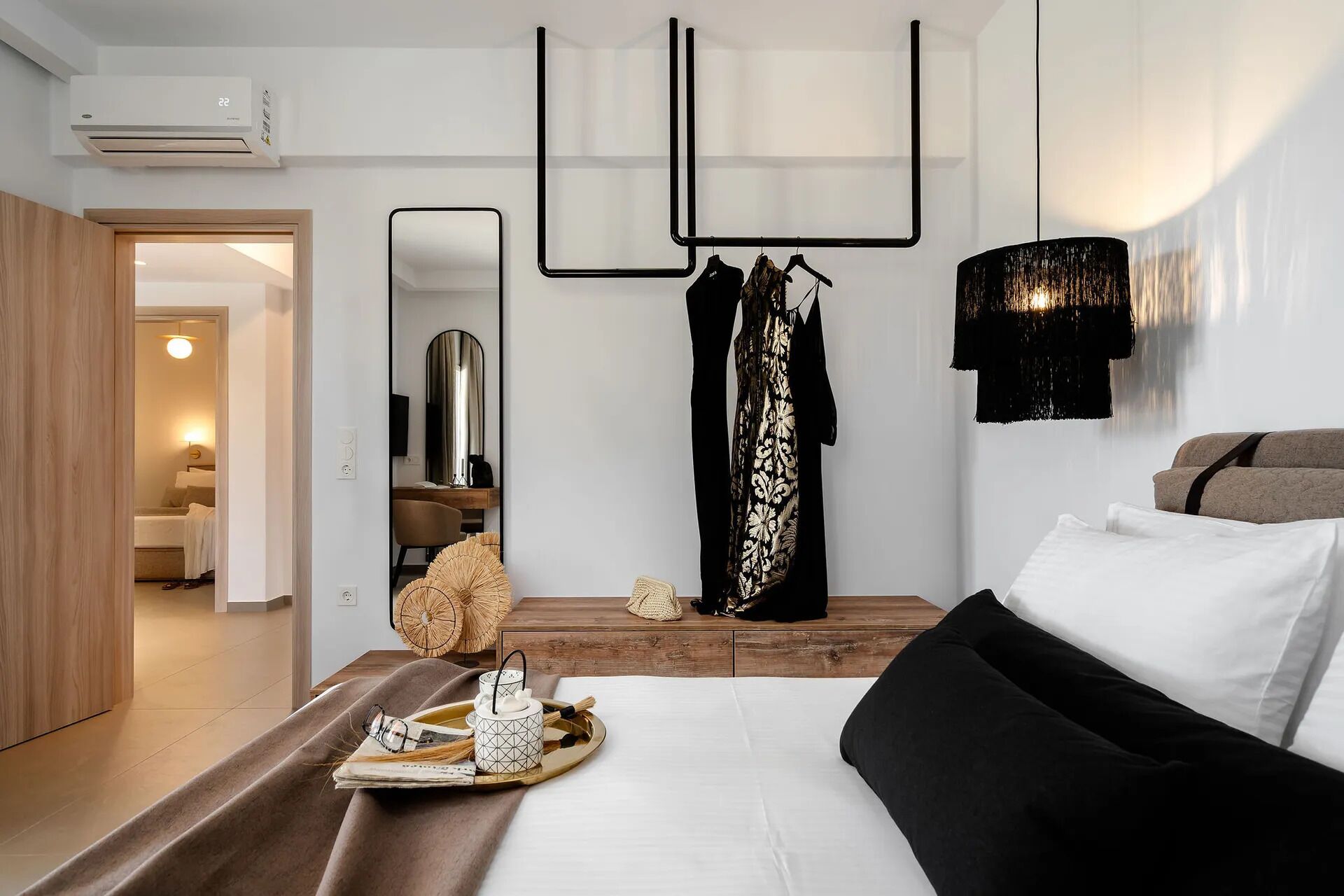 Una habitación de hotel moderna con cama, mesita de noche, espejo y lámpara colgante.