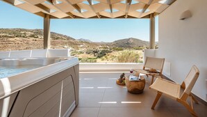 A balcony with a hot tub, wicker chairs, and a view of a mountainous landscape. - Thalelion Villa Private Pool and Jacuzzi (Naxos)