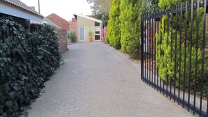 Un sendero pavimentado que conduce a un edificio con un muro de ladrillo y una cerca metálica a un lado.