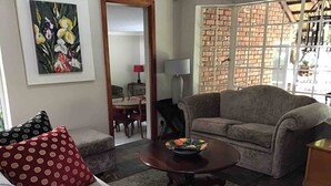 Una sala de estar con sofá, una mesa de centro, un comedor con sillas y una pared de ladrillo.