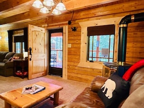 Un interior de madera con un sofá, una mesa de centro, una chimenea y una puerta que da al exterior.